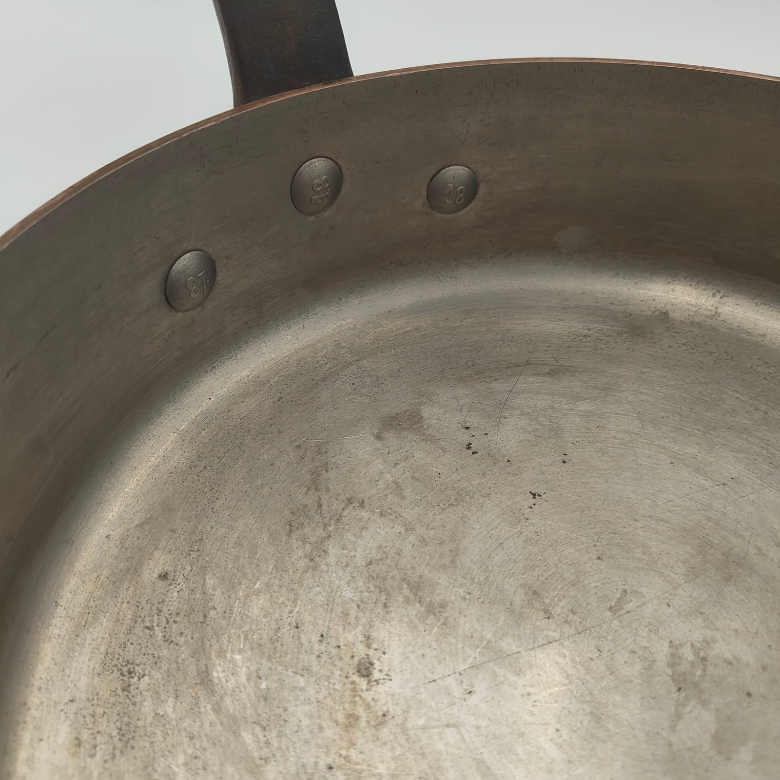Three stamped rivet heads inside an E. Dehillerin copper sauté pan