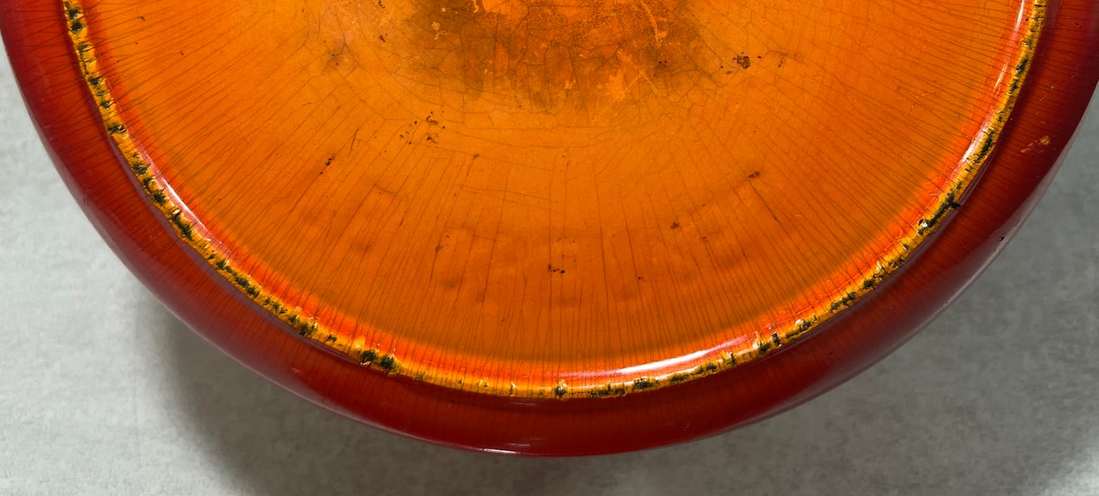 Lower part of the base of an early Le Creuset cocotte, where a cast LE CREUSET legend curves along the foot