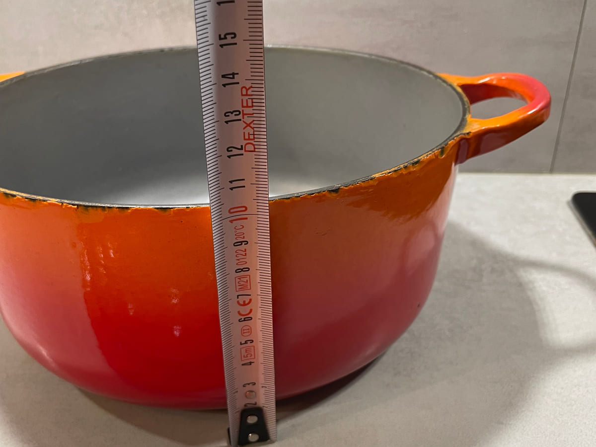 Tape measure held against the body of an early Le Creuset round cocotte to record its height