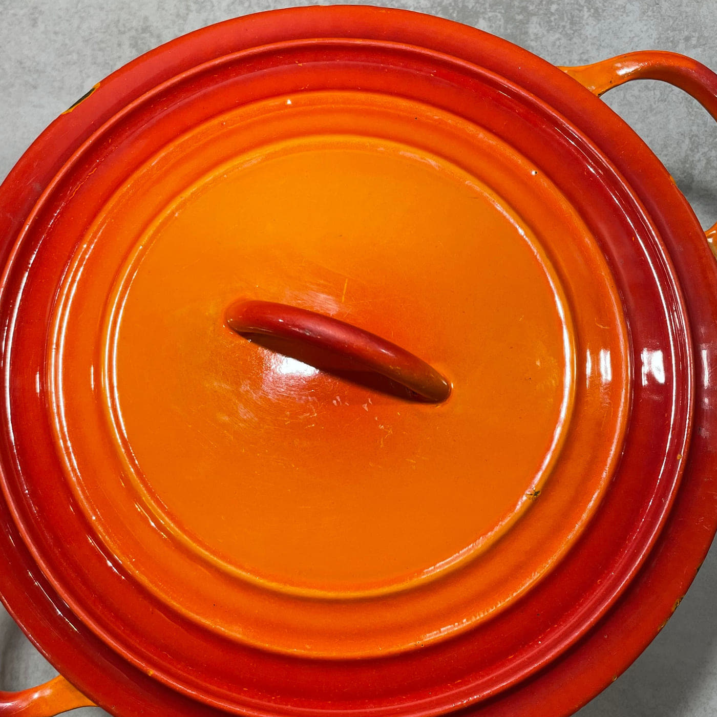Exterior of an early Le Creuset cocotte lid with stepped rings and integral cast handle