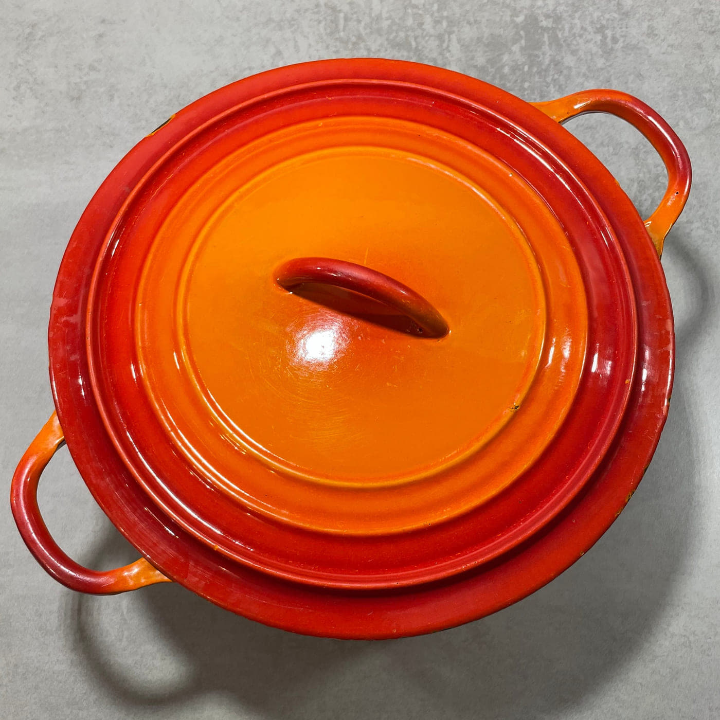 Early vintage Le Creuset round cocotte seen from above, showing the body, both side handles and the integral lid handle